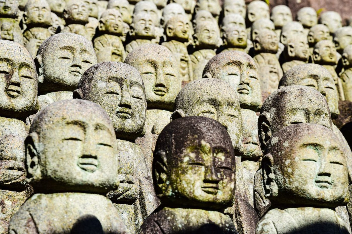 Rows of weathered stone rakan statues at Iwami Ginzan, each face carved differently
