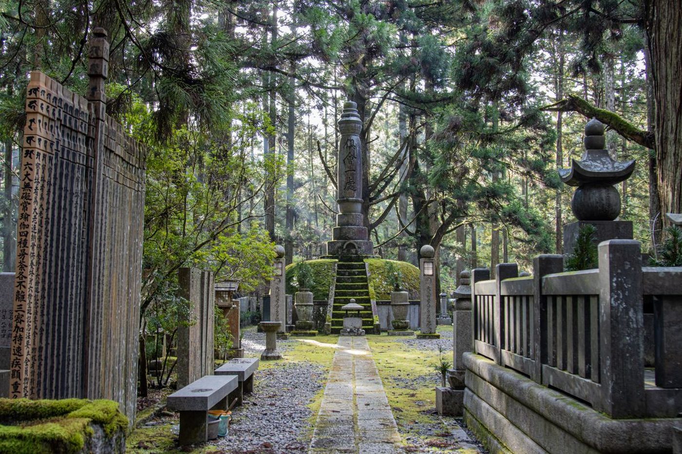 Stone lanterns and moss-covered gravestones lining the cedar path through Okunoin cemetery at Koyasan