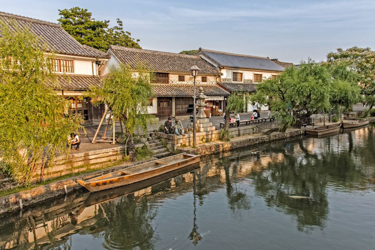 The Kurashiki canal at golden hour — white storehouses and willows along the water
