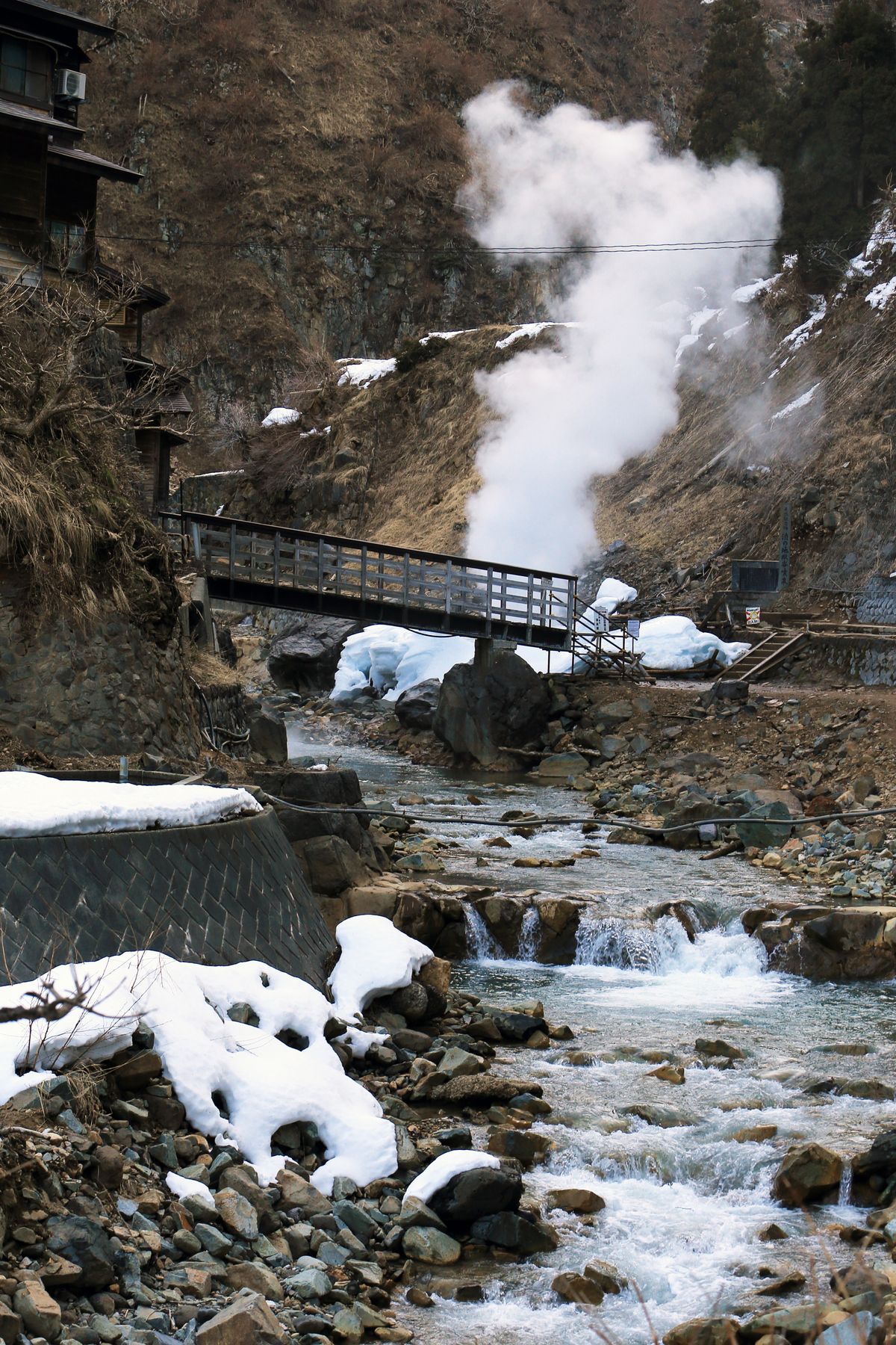 Steam rising from a hot spring source beside a mountain stream in the snow