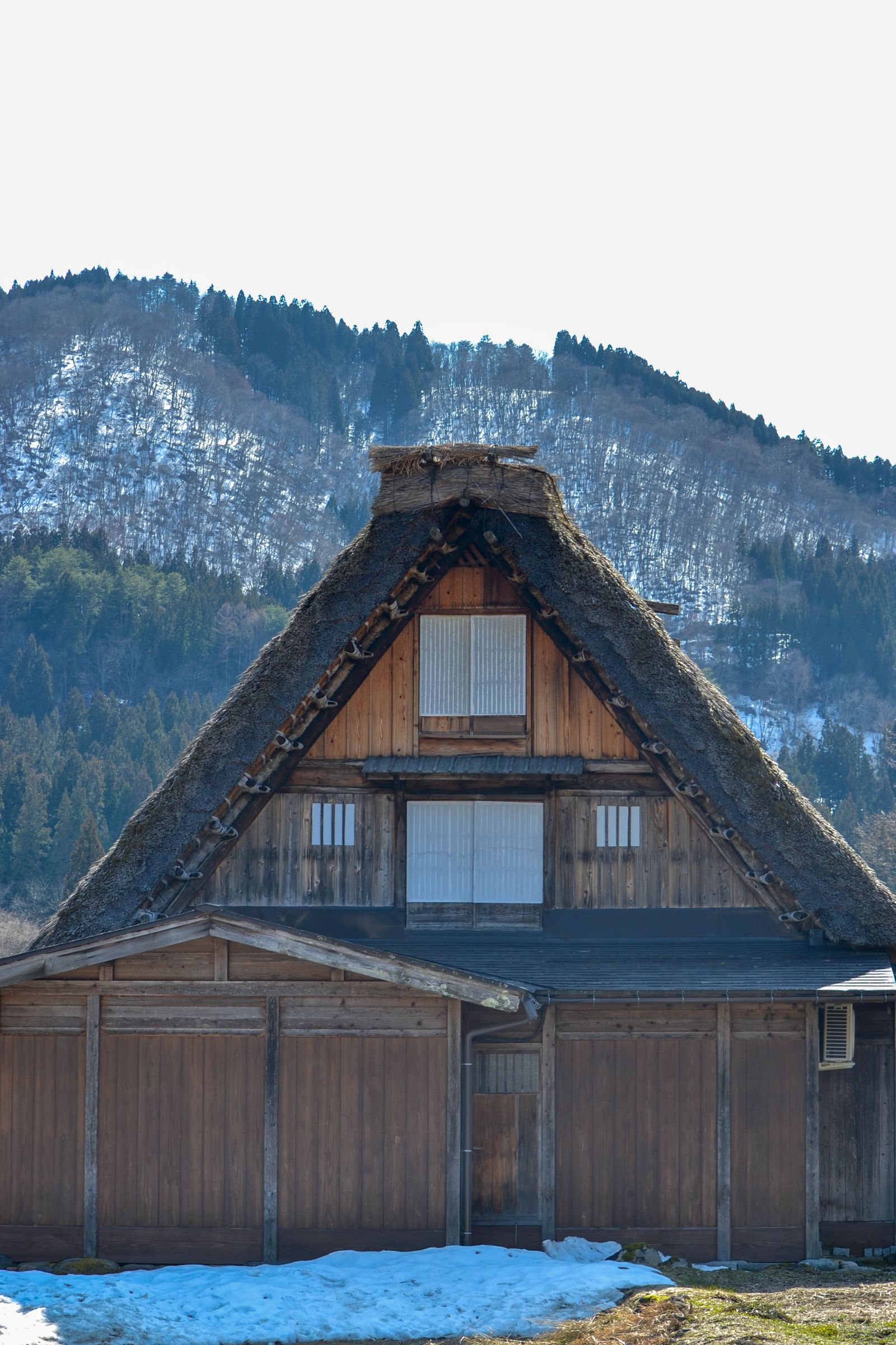 A lone gassho farmhouse against snow-covered mountains at Shirakawa-go