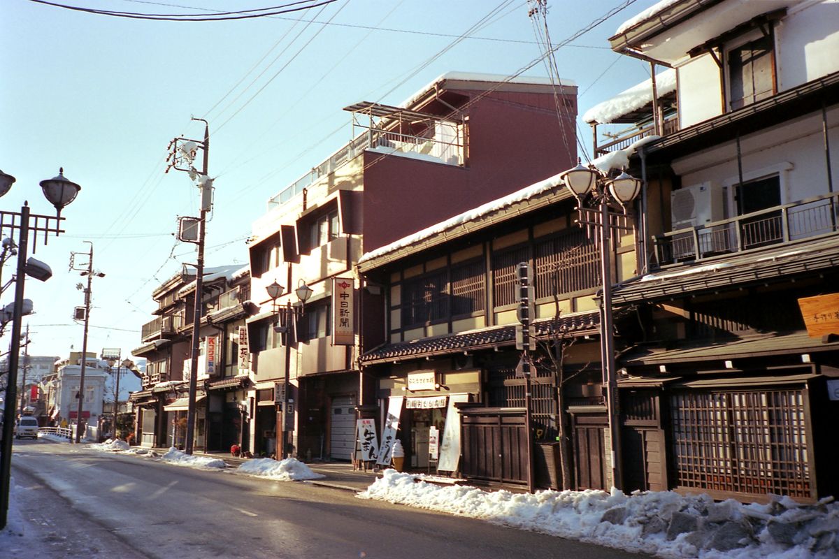 A quiet street of wooden merchant houses under winter snow in Takayama